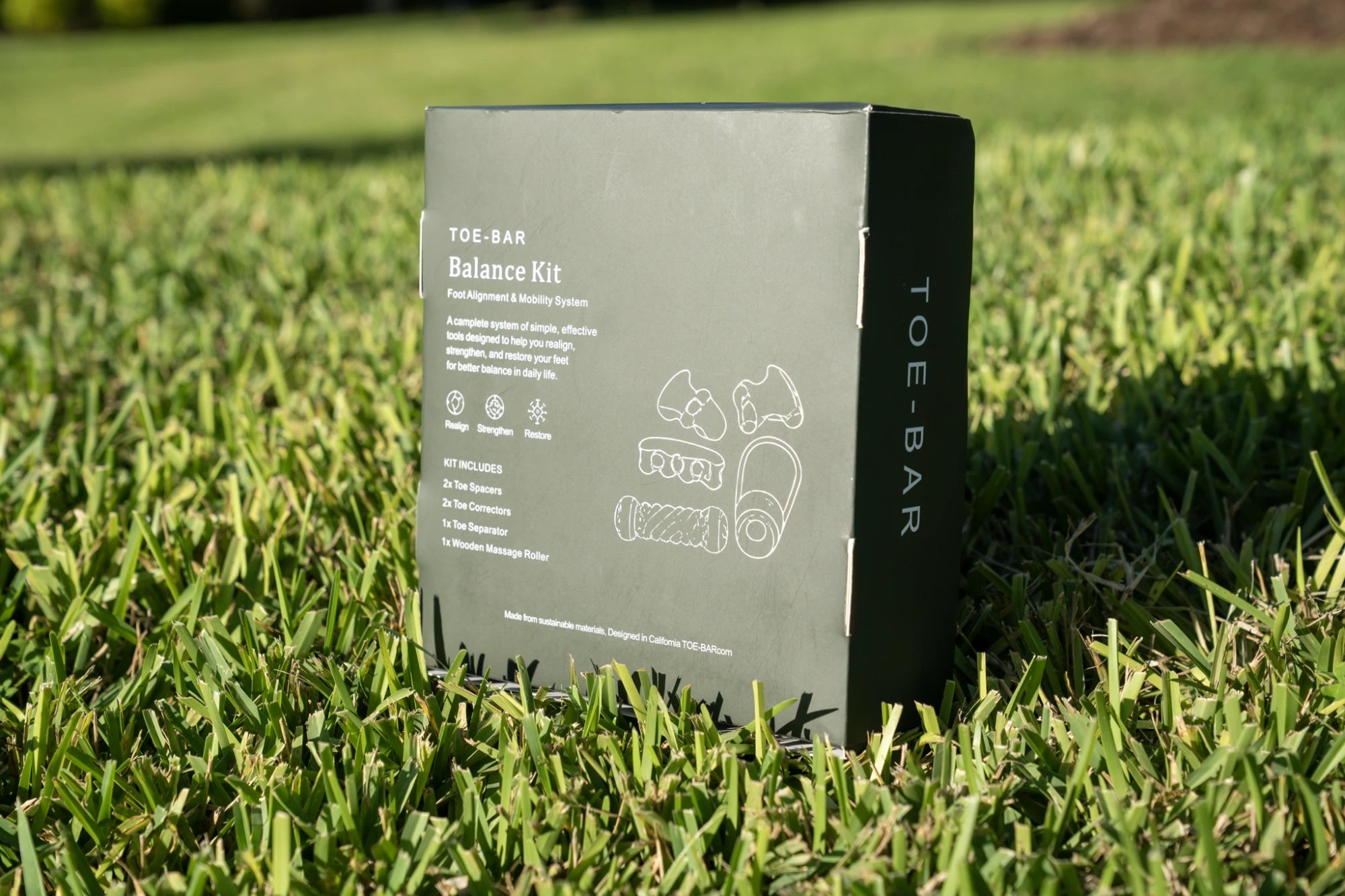 Toe-Bar Balance Kit back of box on grass showing dark green packaging with kit contents list